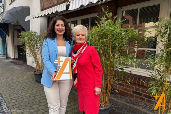 zwei Frauen vor einer Lokalität mit Pro Ahlen Schild in der Hand