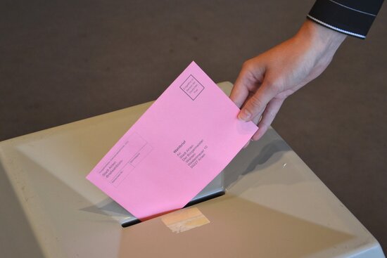 Foto: Wahlurne mit einem Briefwahlumschlag
