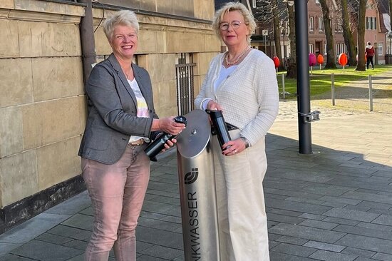 Am Trinkwasserspender vor dem Alten Rathaus empfehlen Claudia Päckert (l.) (Stadtwerke Ahlen) und Klaudia Froede (Stadt Ahlen), immer eine auffüllbare Trinkflasche dabei zu haben.