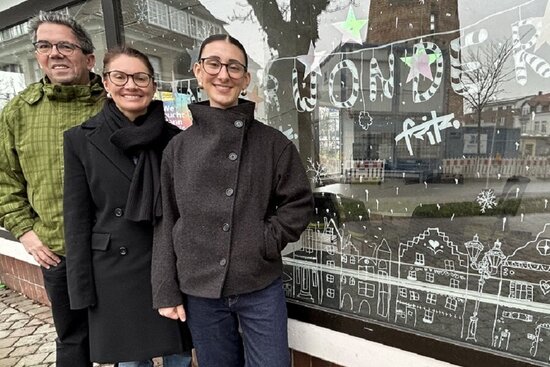 (v.l.): Ralf Grote (Redaktionsteam „Ahlen.de“ und App), Kristina Wotschel und Carlotta Oskamp (FSJ Kultur) vor dem Fenster des Stadtwachtbüros mit weihnachtlicher Stadtlandschaft