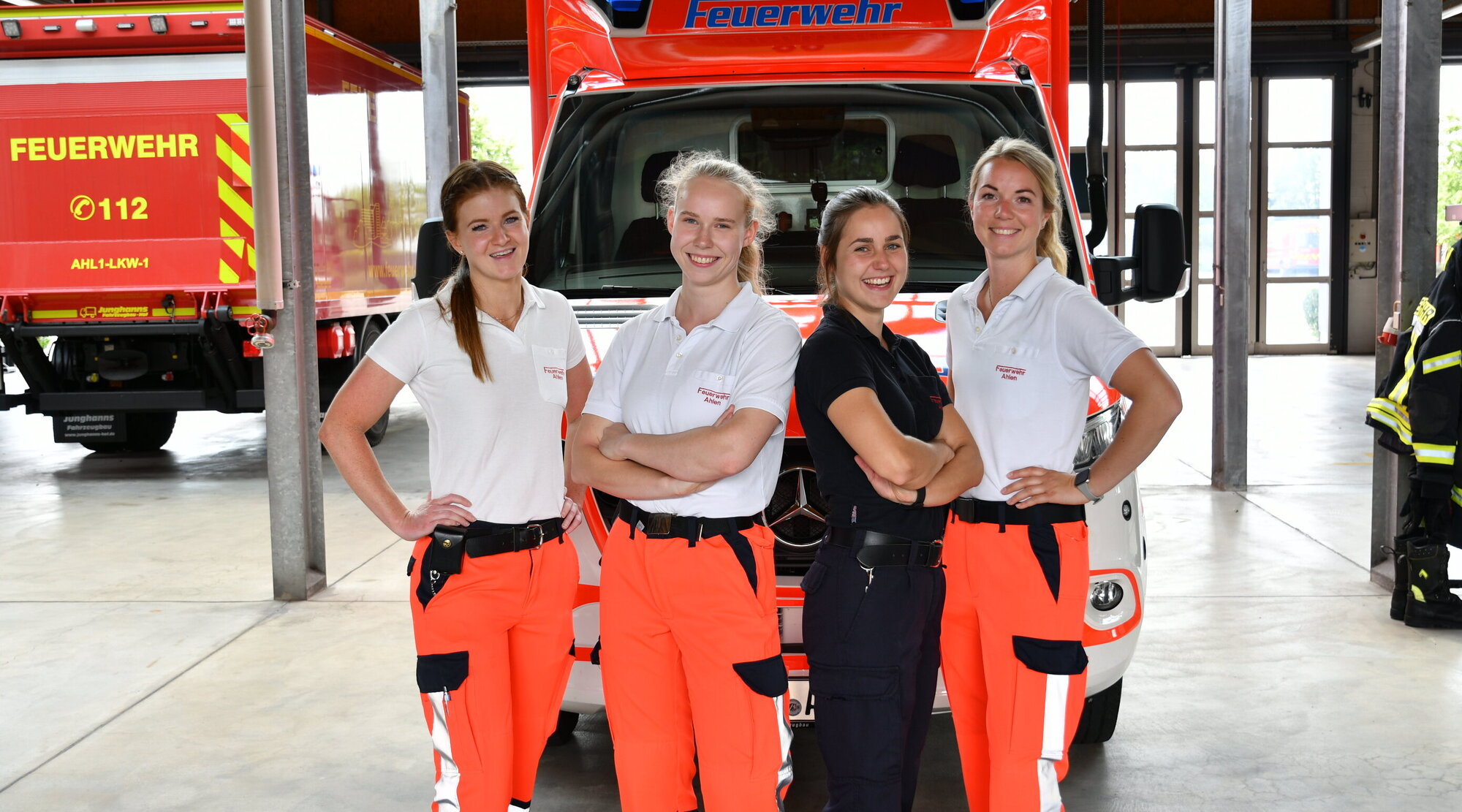 Foto: 4 Notfallsanitäterinnen in der Fahrzeughalle vor einem Rettungswagen