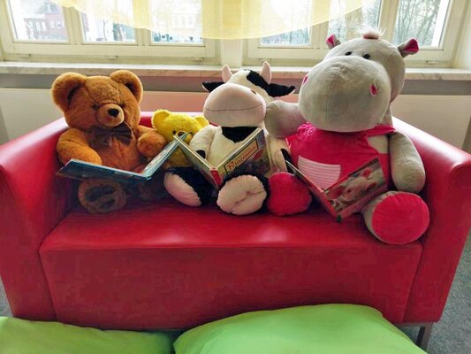 Foto: Stoffbären mit Büchern auf einem Sofa